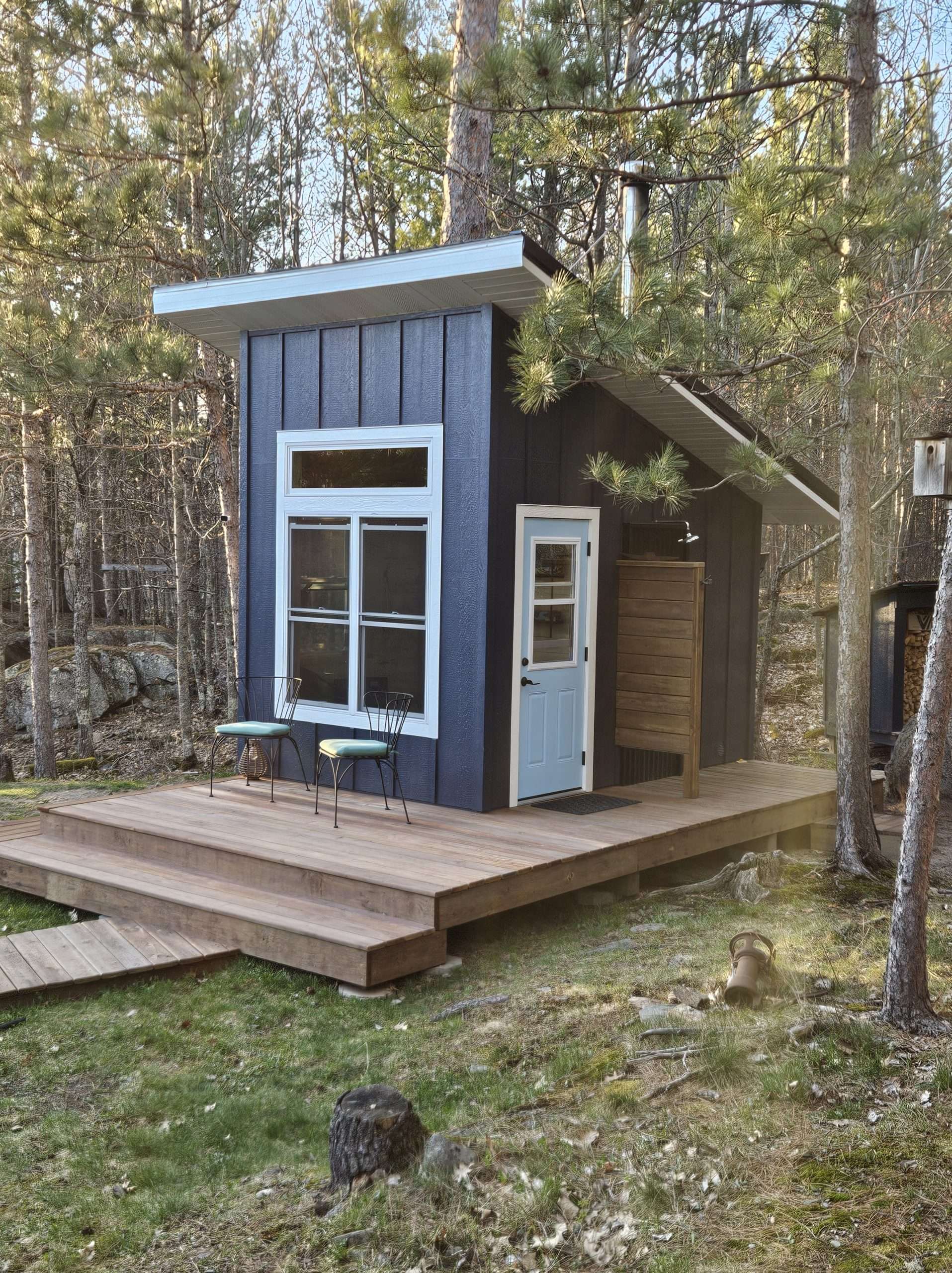 Customer-built backyard wood-fired sauna with a Kuuma BluFlame sauna stove in a wooded setting.